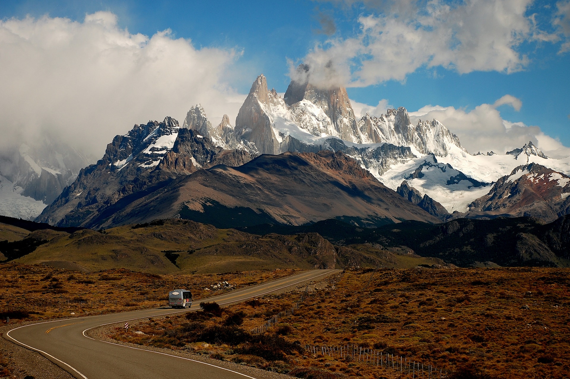 Majestic snow-capped mountains in Patagonia, with a winding road leading through the rugged, windswept landscape.